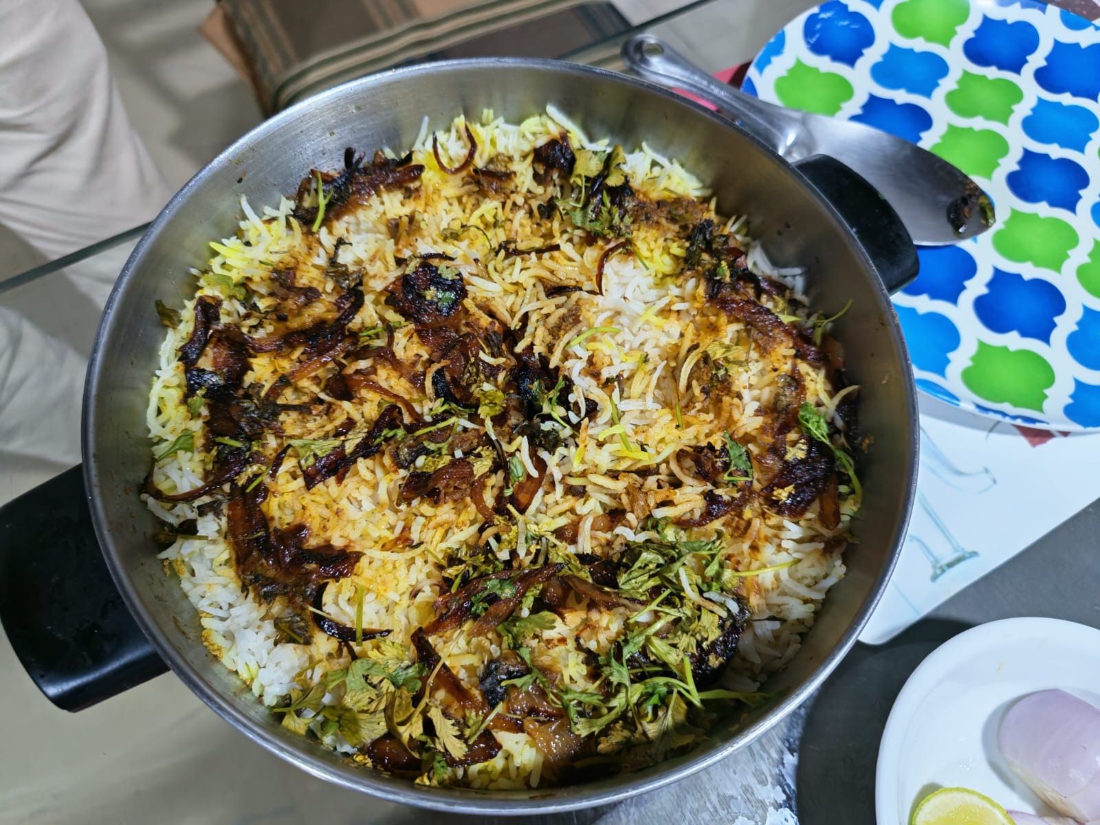 A pan of biryani topped with fried onions and fresh coriander