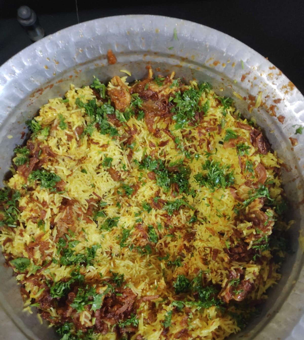 Saffron-yellow biryani in a large hammered pot