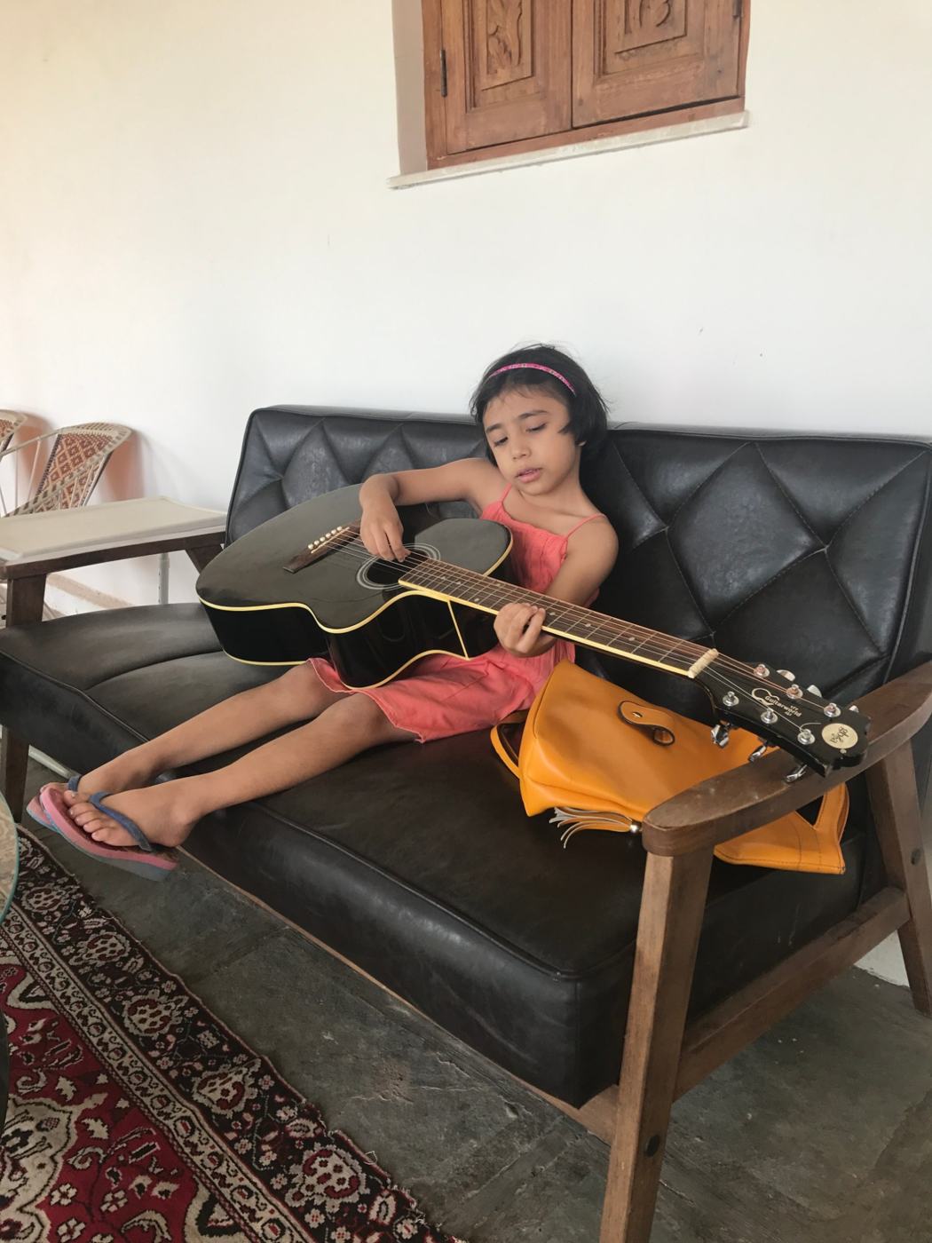 A young guest playing guitar on the sofa