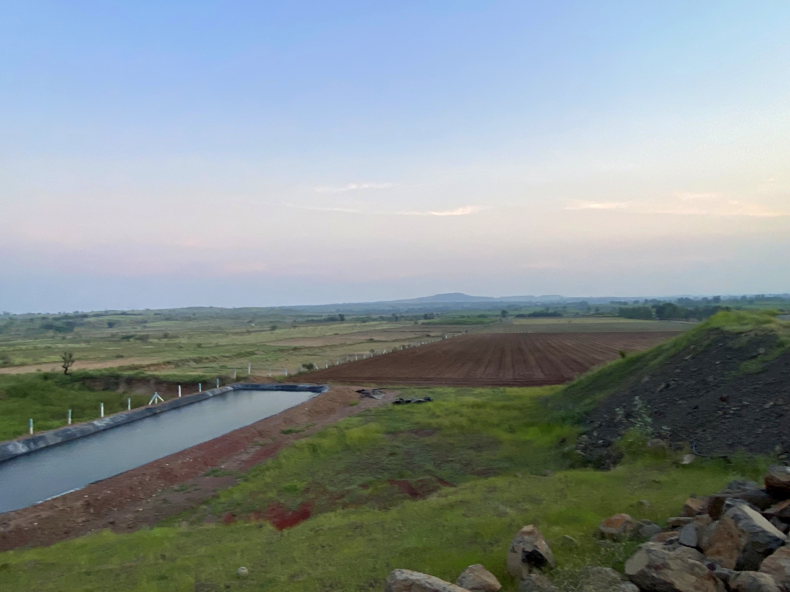 The farm pond and ploughed fields, with hills in the distance