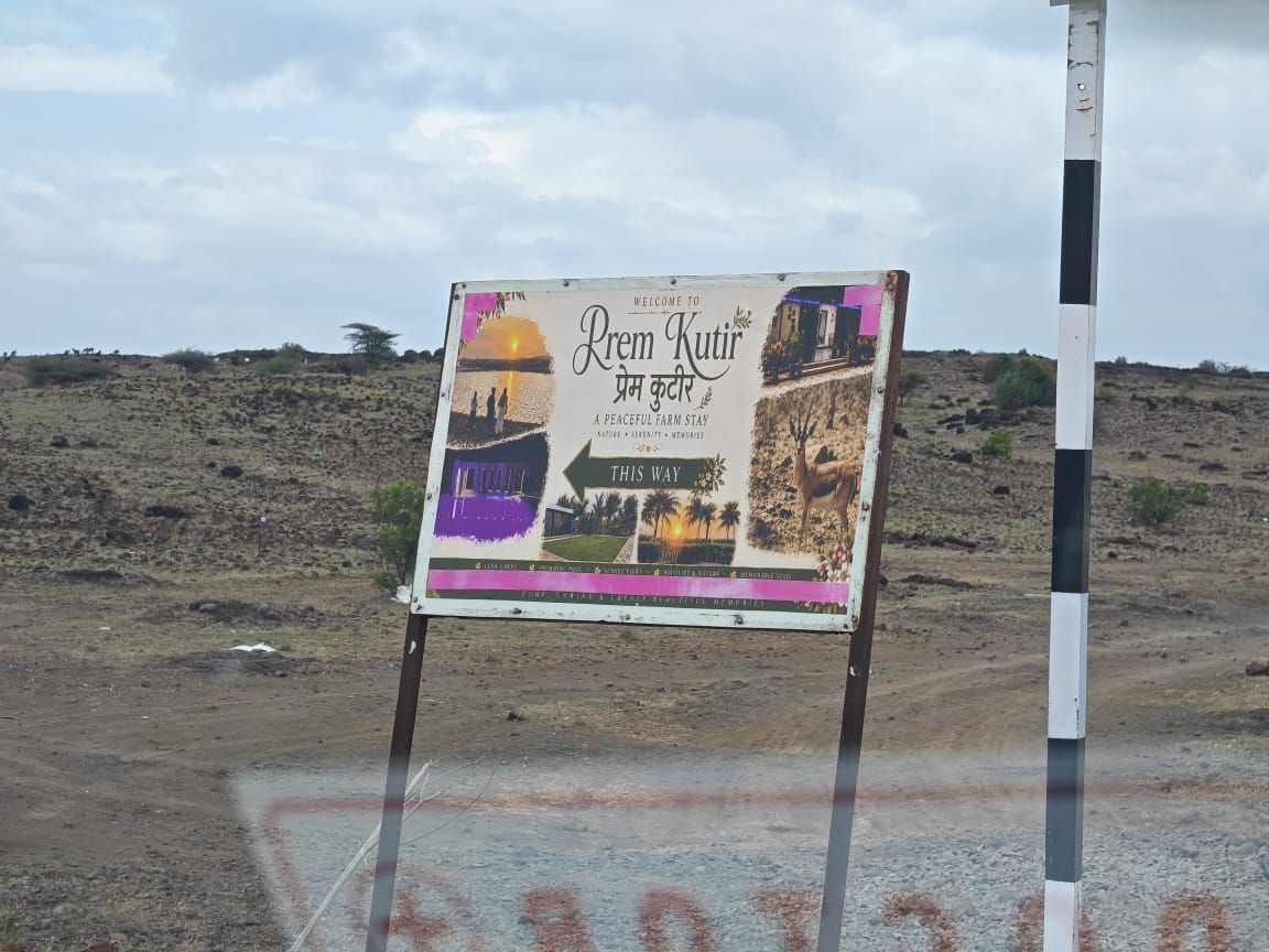 The roadside sign reading Welcome to Prem Kutir, a peaceful farm stay, this way